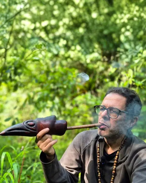 Ramy Shanaytá conduzindo a fumaça com um cachimbo cerimonial, na mata